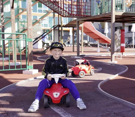 Ein Junge fährt Bobbycar im Freien im Familotel Feldberger Hof.