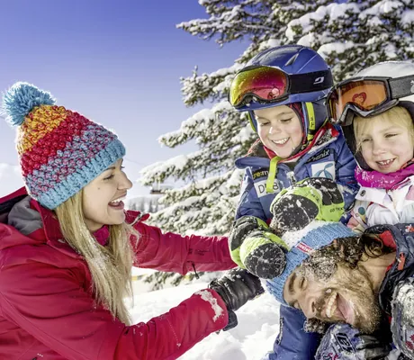 Eine Familie spielt und albert im Schnee herum in der Sonnberg Ferienanlage in Flachau.