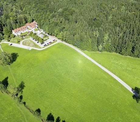 Vogelperspektive vom Ringhotel Sonneck in Bad Wörishofen mit Blick auf grüne Wiesen und Wälder.