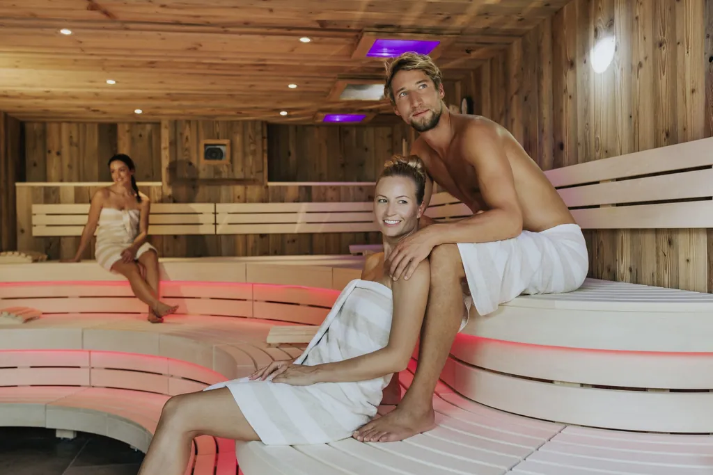 Ein Paar und eine Frau sitzen in der Sauna im Ortners Resort in Bad F&uuml;ssing.