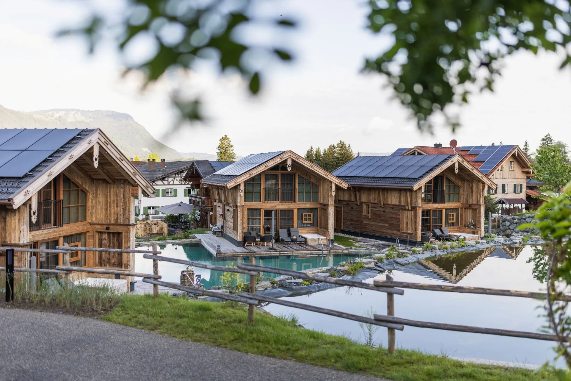 Mehrere Alpzitt-Chalets mit Holzfassade, Terrasse und Naturbadesee