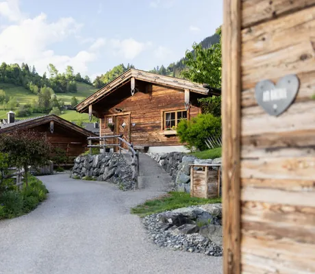 Rustikale Alpzitt-Chalets in einer grünen Berglandschaft, mit gepflegten Wegen und Pflanzen