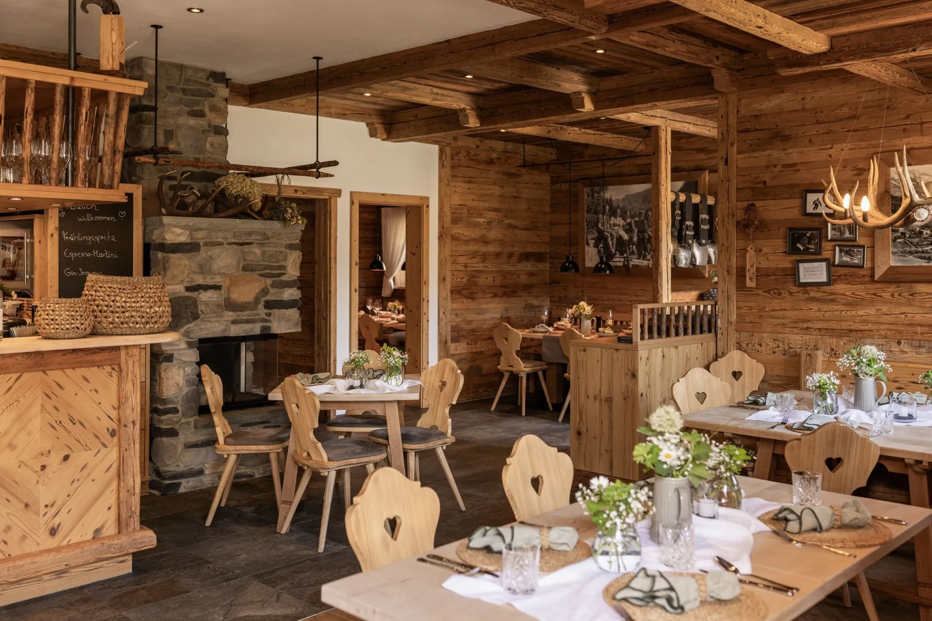 Gemütliches, rustikales Restaurant der Alpzitt-Chalets mit Holzinterieur, gedeckten Tischen und Kamin im Hintergrund