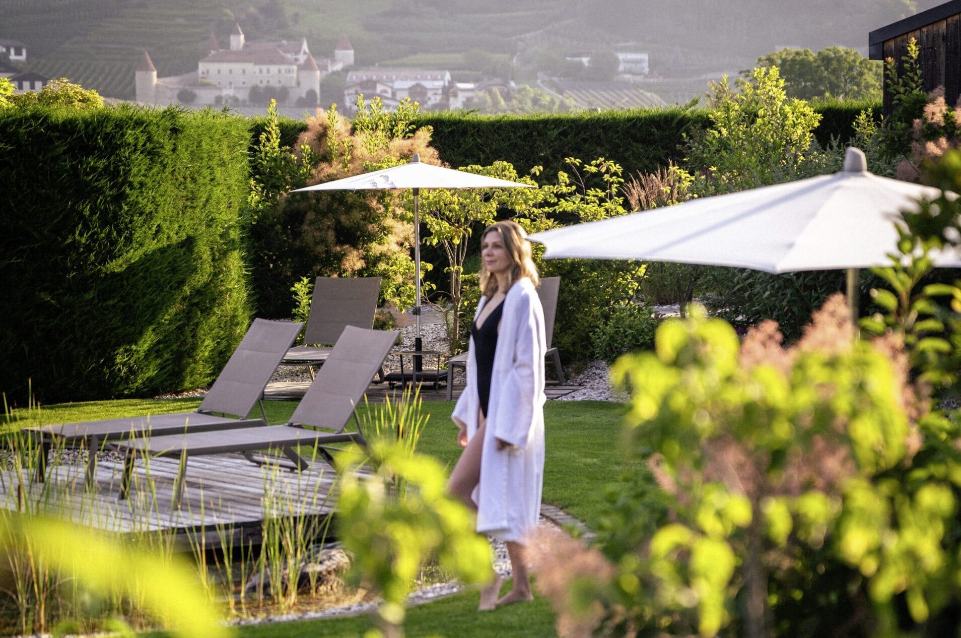 Eine Frau im Bademantel steht im Garten des Amolaris Garden Lodge & Guesthouse in Goldrain.