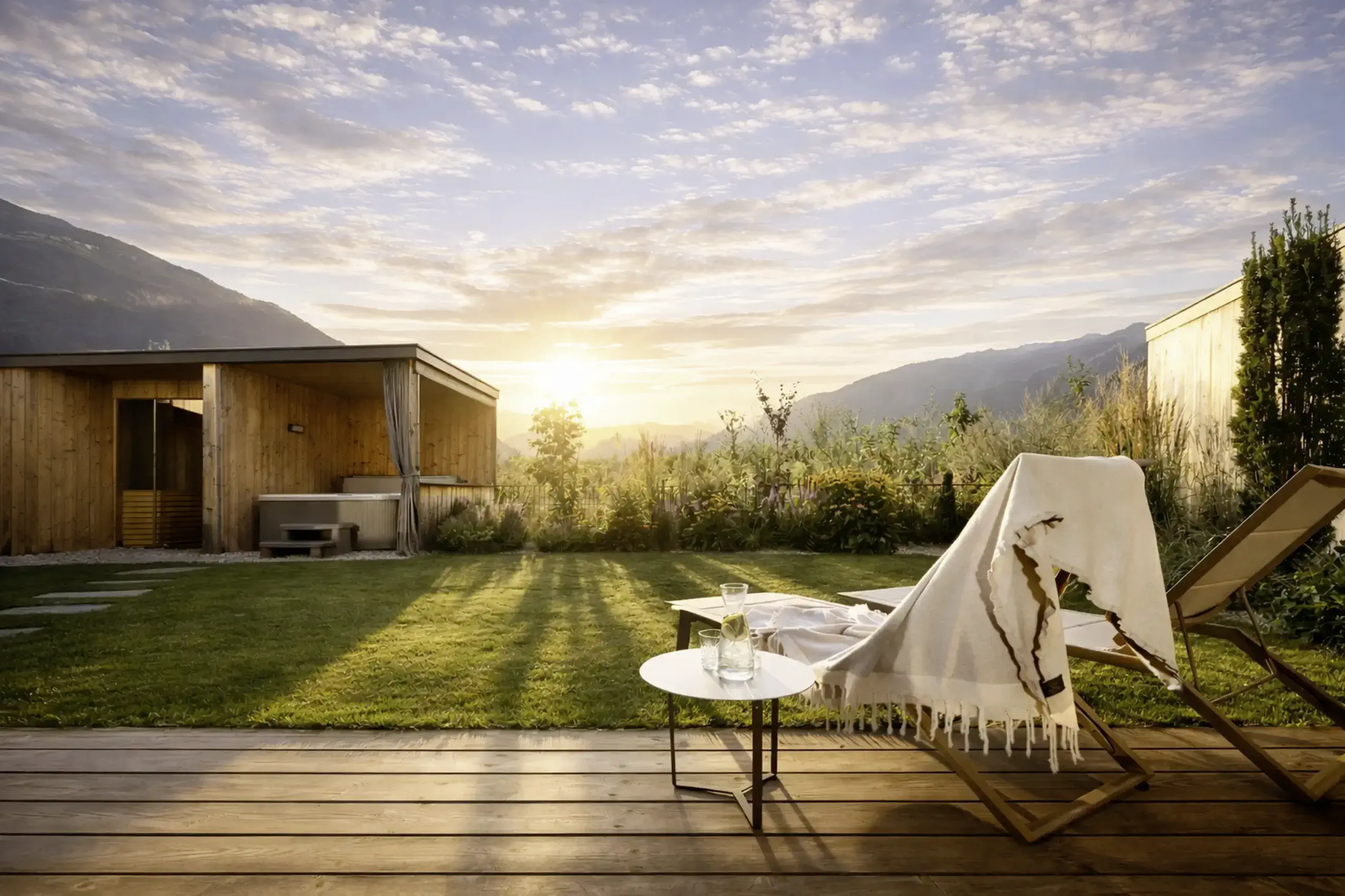 Sonnenuntergang auf der Außenterrasse im Amolaris Garden Lodges & Guesthouse in Goldrain mit Blick auf ein Chalet.