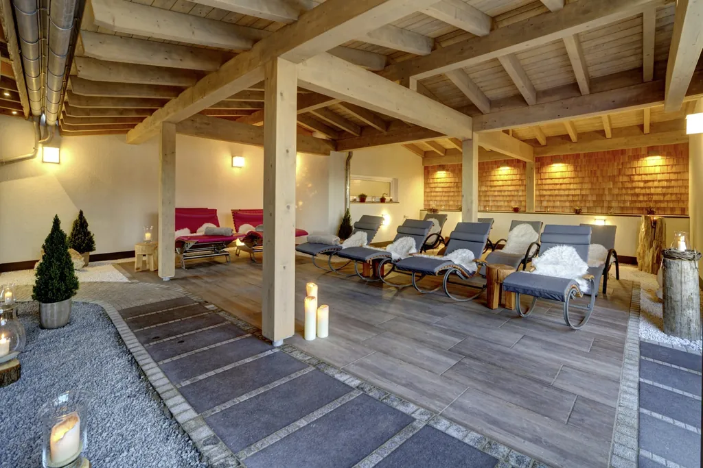 Der &uuml;berdachte Ruhebereich im Wellnesshotel Hofbr&auml;uhaus mit gem&uuml;tlichen Schaukelst&uuml;hlen und Liegen mit Lammfell und warmer Beleuchtung.