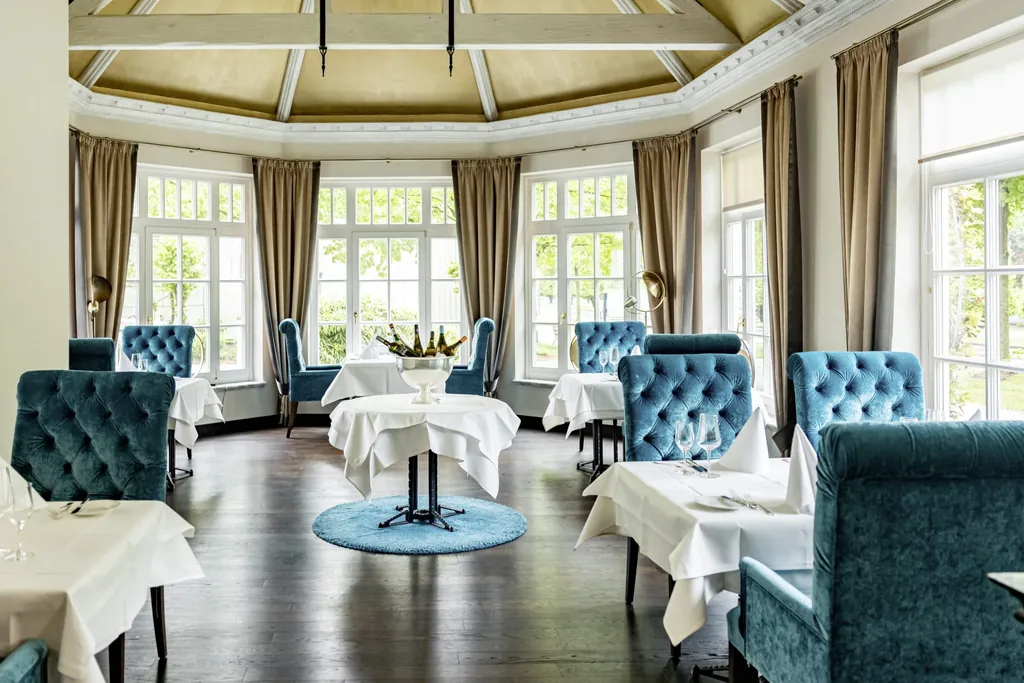 Das Restaurant des Hotel Holzapfels mit blauen Samtsesseln und gedeckten Tischen.