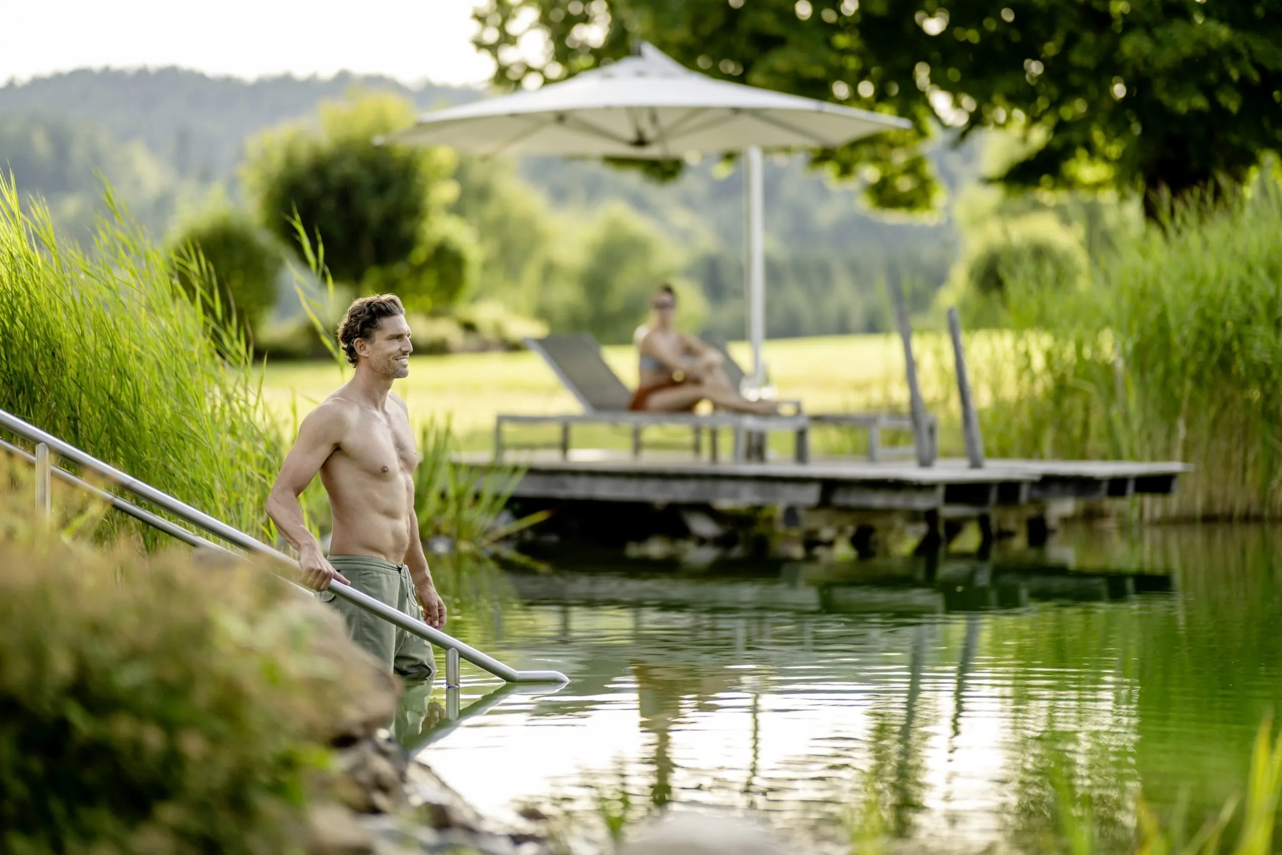 Ein Mann geht im Hotel Mooshof Wellness & Spa Resort in den hoteleigenen Naturbadesee.