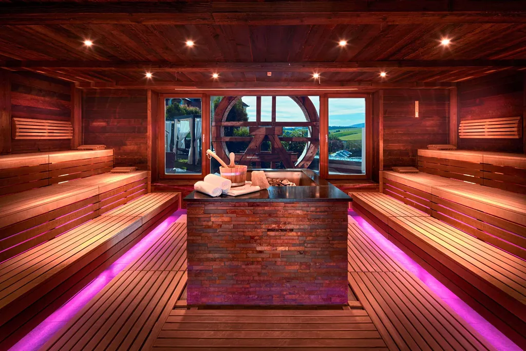 Panoramasauna in pink-rot im Wellness- und Sporthotel Jagdhof mit indirekter Beleuchtung unter den Holzb&auml;nken.