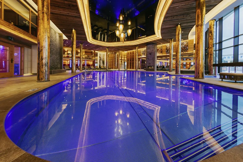 Indoorpool im Ortners Resort in Bad F&uuml;ssing mit goldenem Licht und stilvollen Dekoelementen.