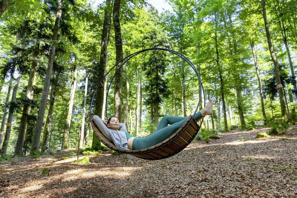 Eine Frau in der Baumschaukel im WaldSpa im Wellness- und Naturresort Reischlhof mitten im Gr&uuml;nen.