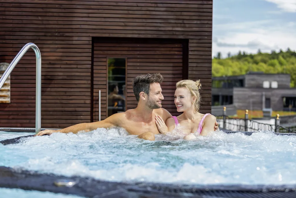 Ein Paar genie&szlig;t und lacht im Whirlpool des Wellness- und Naturresort Reischlhof in Wegscheid.