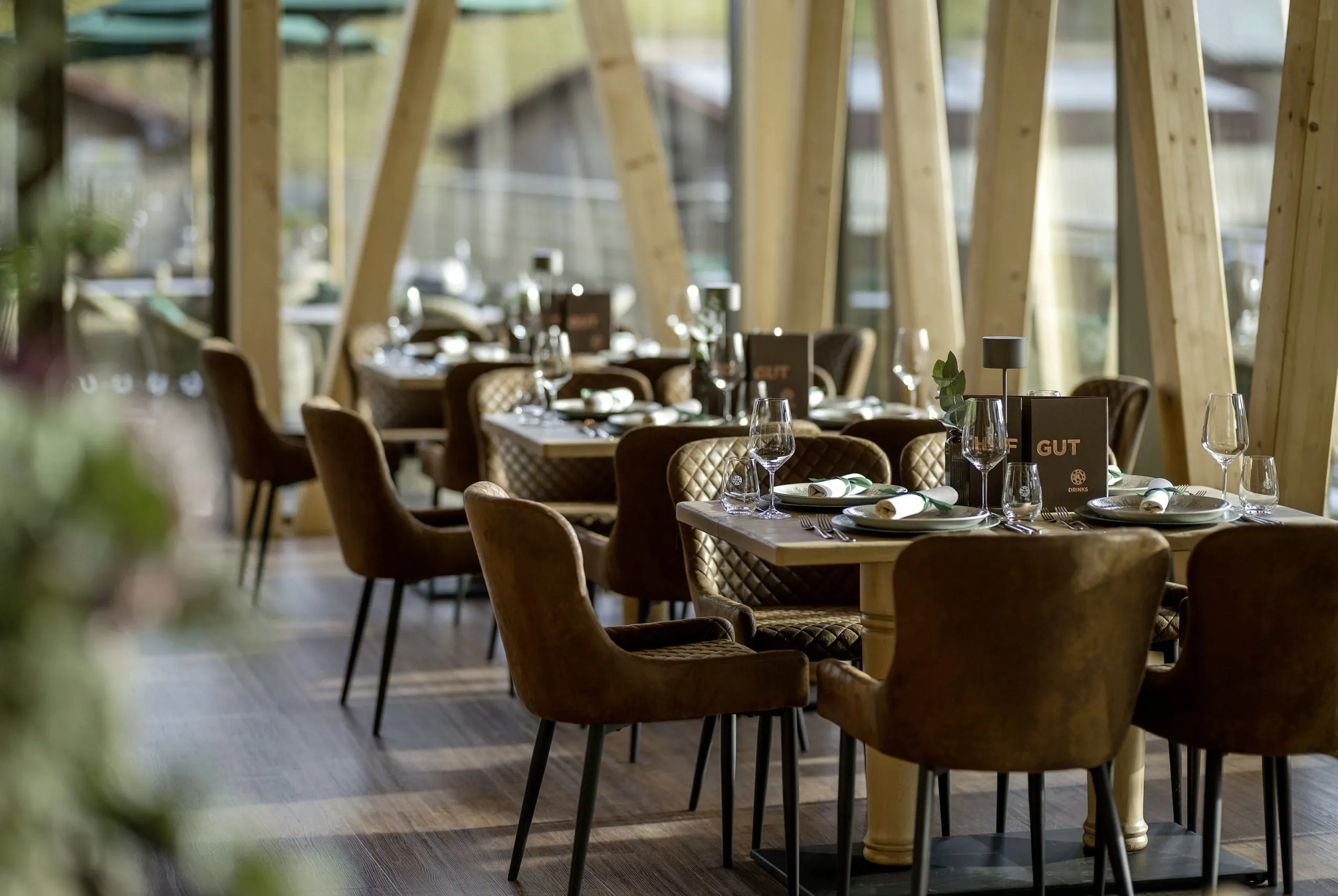 Der Restaurantbereich im Sonnenalp Resort mit braunen Samtlederst&uuml;hlen und Holz-Interieur.