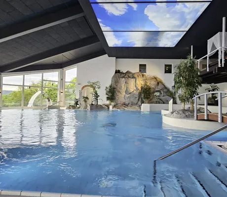 Indoorpool in Göbels Hotel Rodenberg mit Felsenwand und Wolkendach