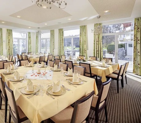 Gedeckte Tische, die als Gruppen im Tagungsraum im Ringhotel Sonneck zusammengestellt wurden mit Blick auf die Sonnenterrasse.