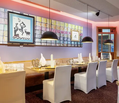 Das moderne Restaurant Picasso im Ringhotel Sonneck mit gedeckten Tischen und Stühlen, die mit weißen Stuhlhussen überzogen sind.