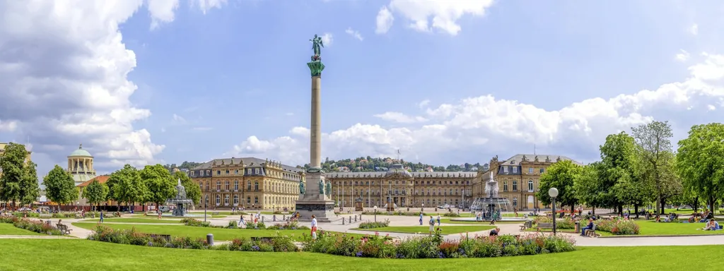 Schlossplatz in Stuttgart mit König-Wilhelm-Denkmal, historischem Gebäudeensemble und gepflegten Grünflächen unter blauem Himmel