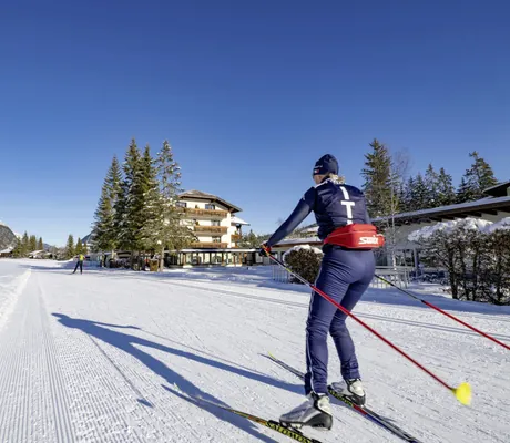 Langäufer in blauerm Outfit auf der Loipe vor dem Alpenhotel Karwendel