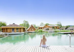 Frau sitzt am grünen Teich mit Holzhütten im Best Western Plus Kurhotel an der Obermaintherme