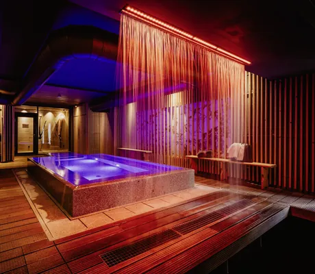 blau beleuchteter Indoorpool mit Wasservorhang im Bodenmaiser Hof