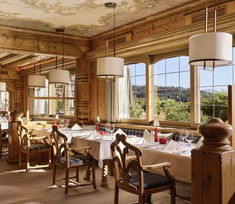 Traditionelle Tiroler Stube im Interalpen-Hotel Tyrol mit Holzinterieur, gedeckten Tischen und dekorativen Deckenmalereien