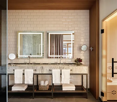 Modernes Badezimmer einer Suite im Interalpen-Hotel Tyrol mit Doppelwaschtisch, Spiegelbeleuchtung und privater Sauna