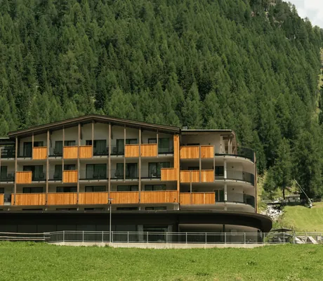 Außenfassade des My Paradies mit Wald und Fichtenbäumen im Hintergrund.