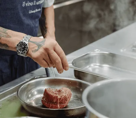 Ein Koch mit Tattoos bereitet im My Paradies in Sulden ein Steak zu.