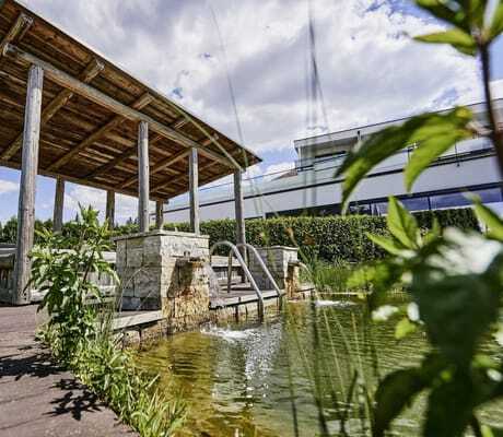 Outdoor-Liegefläche mit Holzdach am Teich des Wellnesshotel Zum Bräu