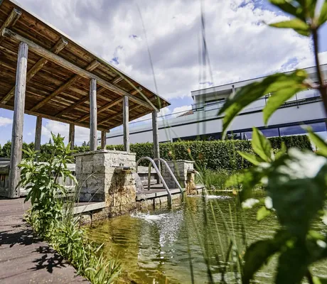 Outdoor-Liegefläche mit Holzdach am Teich des Wellnesshotel Zum Bräu