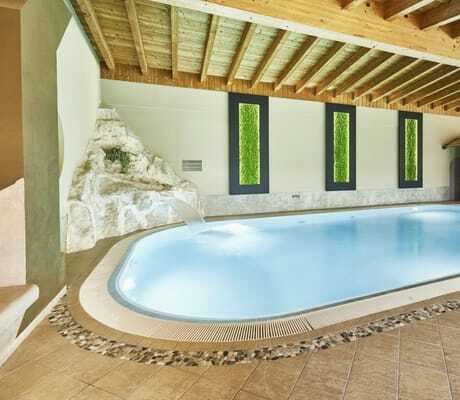 rund angelegter Indoorpool im Wellnesshotel Zum Bräu mit Wasserschwall, der au seinem künstlichen Felsen kommt