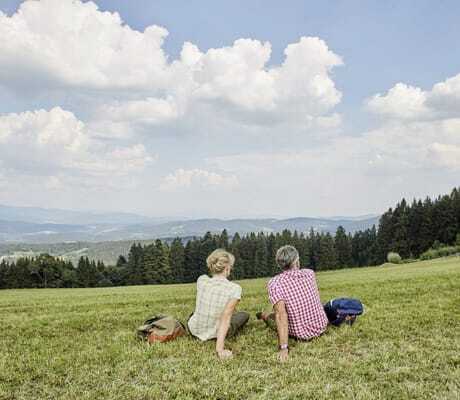 Paar in Karohemden sitzt auf der Wiese des Wellnesshotel Zum Bräu und schaut in die Ferne