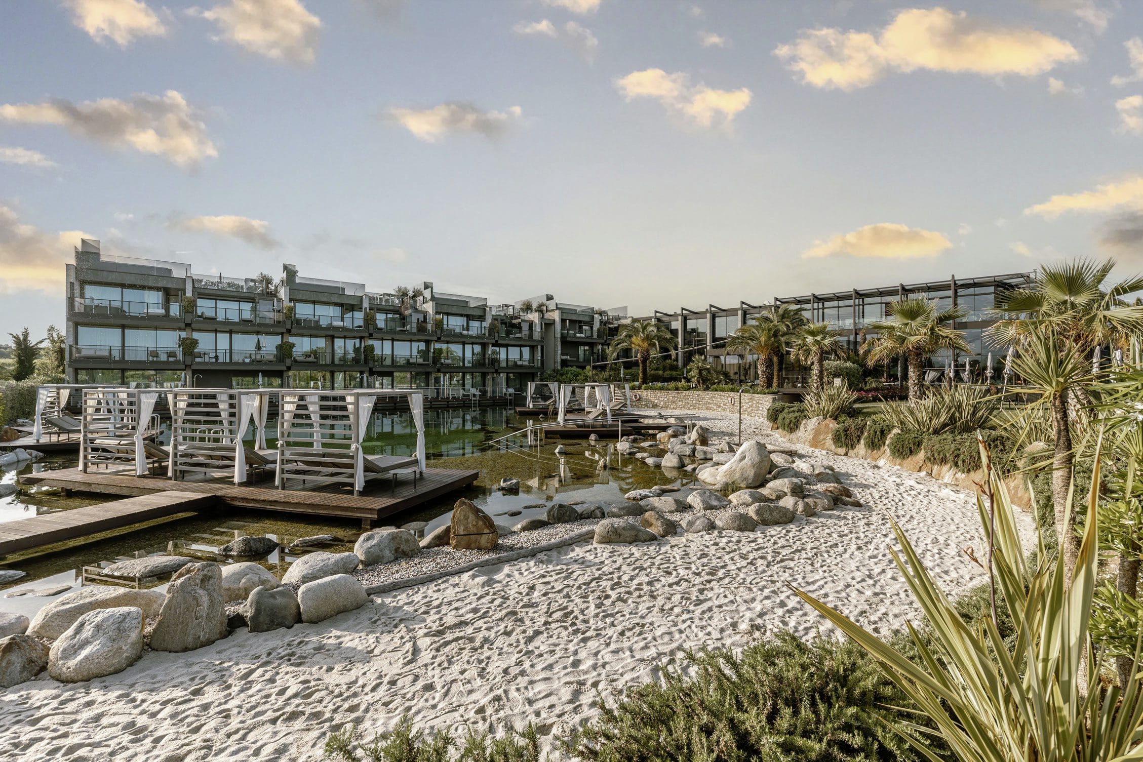 weißer Sandstrand am Naturteich mit Daybeds im Quellenhof Luxury Resort Lazise