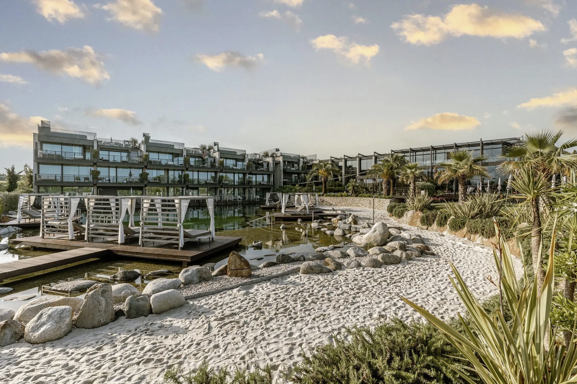 weißer Sandstrand am Naturteich mit Daybeds im Quellenhof Luxury Resort Lazise
