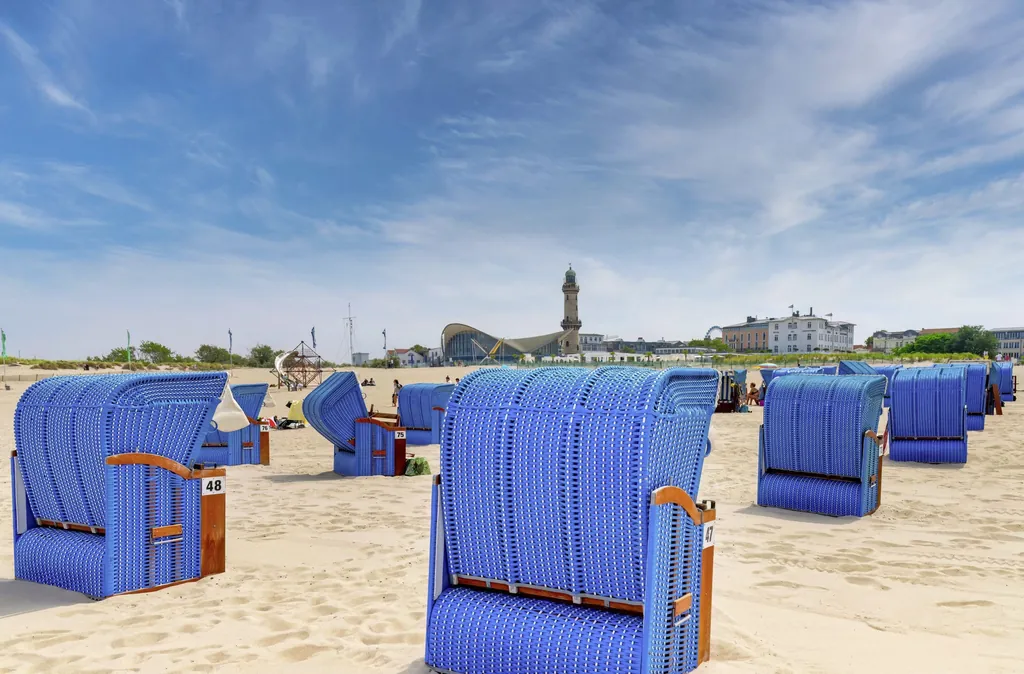 Heller Sandstrand von Warnemünde mit blauen Strandkörben, Blick auf den Leuchtturm und Teepott
