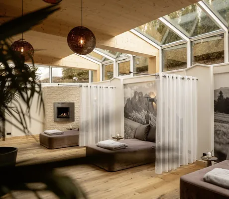 Gemütlicher Ruheraum mit Liegen, Vorhängen und Kamin unter einer gläsernen Dachkonstruktion im Das Parkhotel