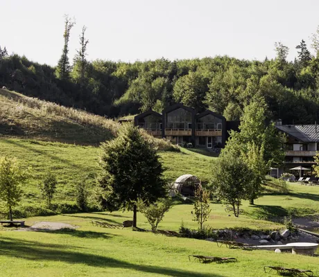 Außenansicht des Berghotel Schlossanger Alp mit neuen Suiten im Hang und Naturteich