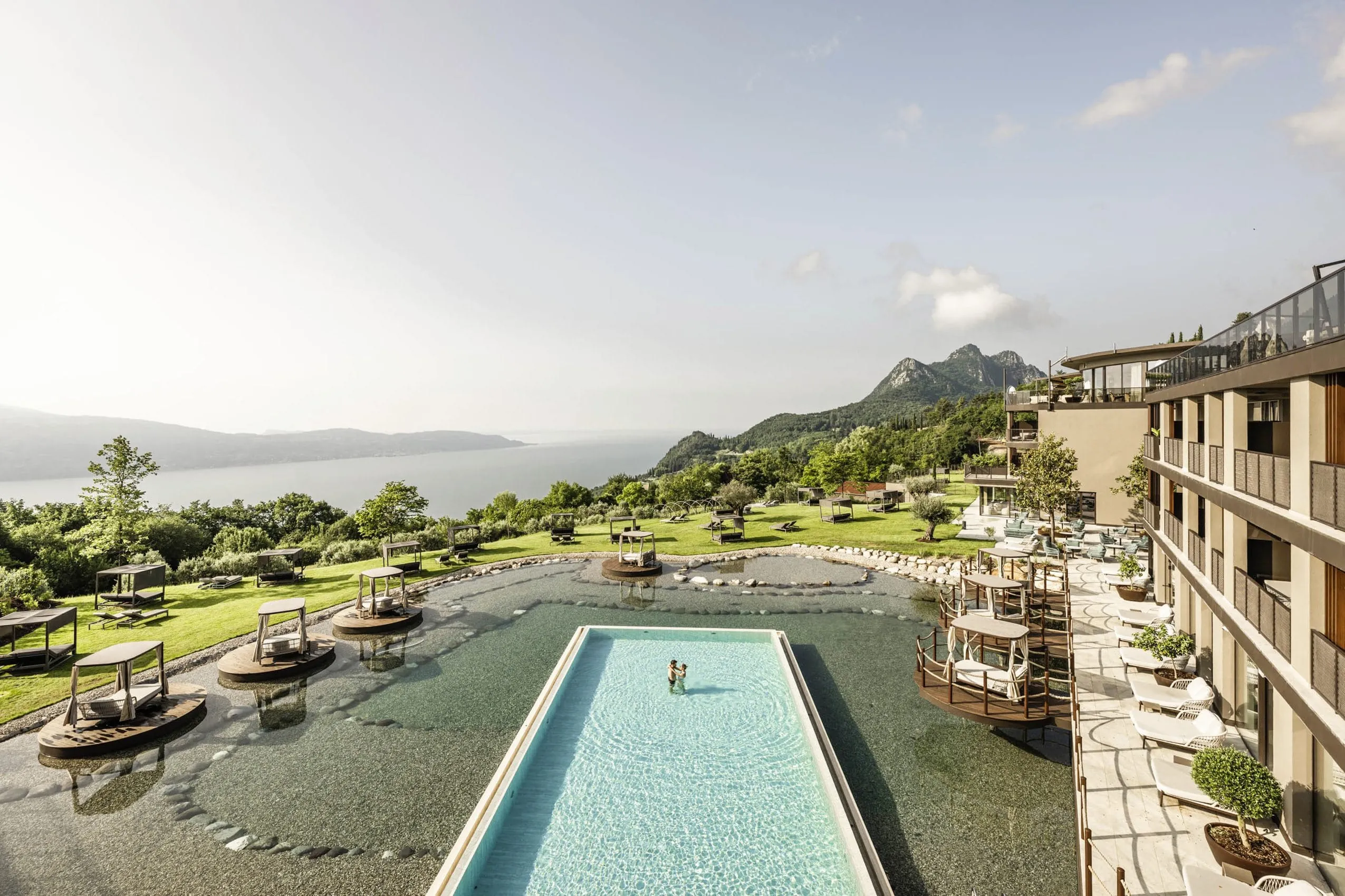 Ansicht der Lage des Stroblhof Lake Garda oberhalb vom Gardasee mit Outdoorpool und Schwimminseln im Badeteich