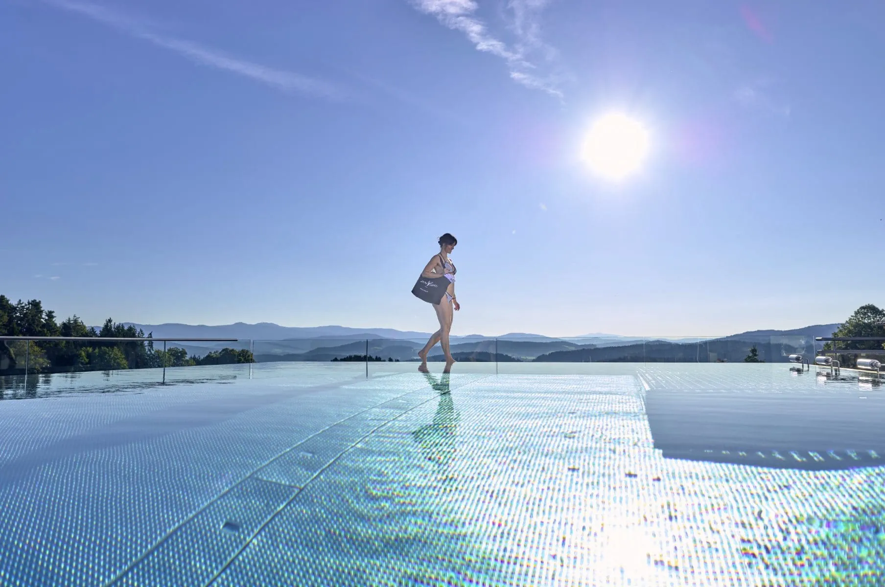 Frau im Bikini geht am Rand des Infinitypools im Adults only-Wellnesshotel Zum Bräu