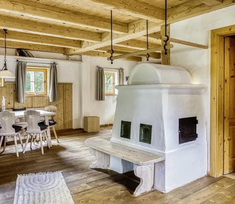 Gemütlicher Essbereich in einem der Chalets des Naturresort PURADIES mit Holzmöbeln, einem Kachelofen und sichtbaren Holzdeckenbalken