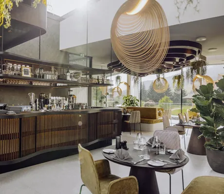 Modernes Gourmetrestaurant im Naturresort PURADIES mit eleganter Bar, Designerleuchten und Panoramablick auf die Umgebung