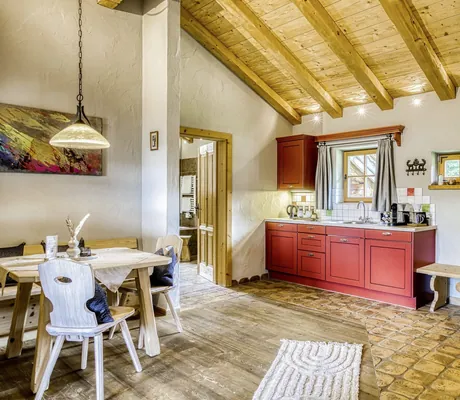 Offene Küche mit roten Schränken, angrenzendem Essbereich und rustikaler Einrichtung im Chalet-Stil in einem Chalet des Naturresort PURADIES