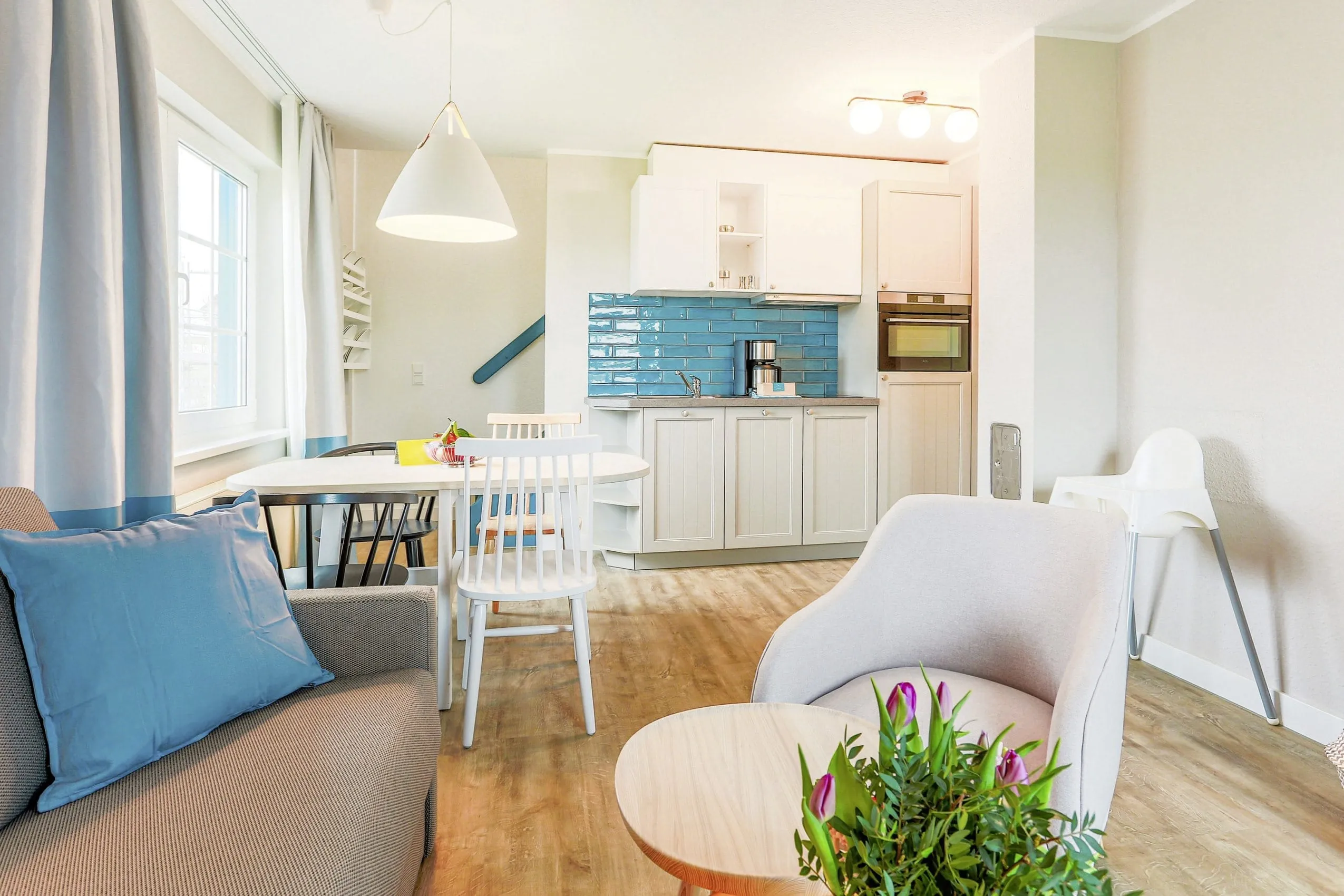 Appartement im BEECH Resort Fleesensee mit türkisen Kacheln in der Küchenzeile und weißer Hängelampe