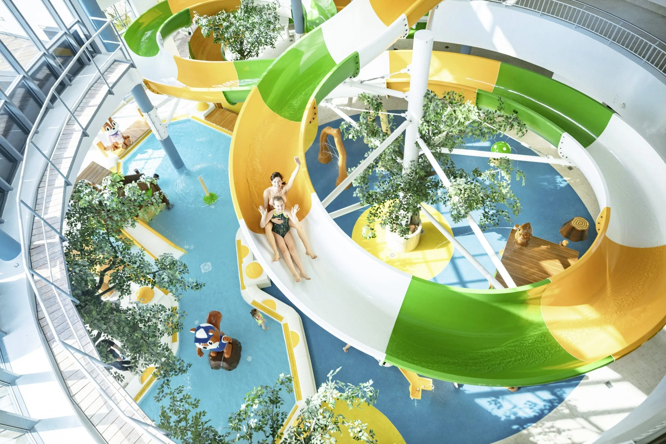 Mutter und Kind rutschen auf großer, bunter Wasserrutsche im Aquafun-Erlebnisbad