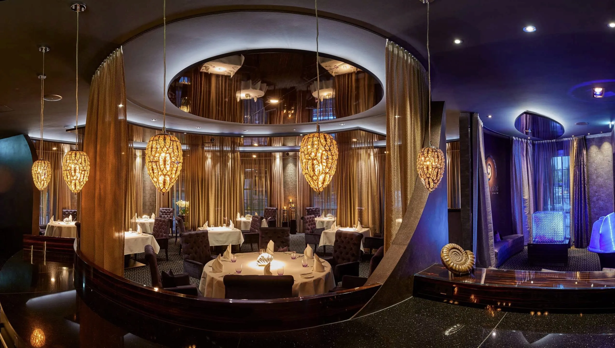 Sternerestaurant Ammolite mit gedeckten Tischen und zapfenförmigen Lampen im Erlebnishotel Bell Rock Europa-Park in Rust