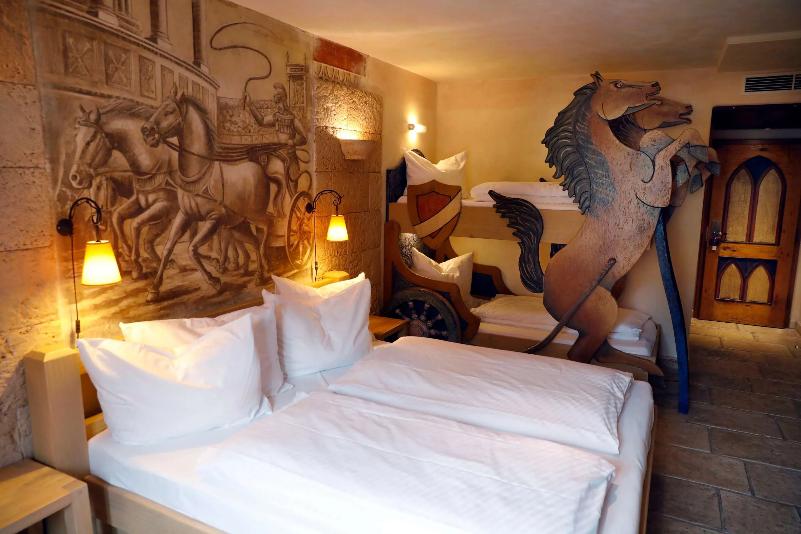 Familienzimmer im Erlebnishotel Colosseo Europa-Park in Rust mit römischem Wandgemälde, thematischer Holzeinrichtung und Stockbett im Pferdewagen-Design
