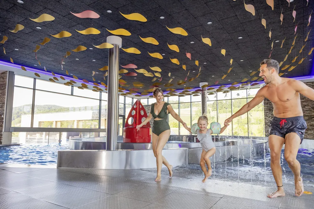 Vater, Mutter, Tochter Hand in Hand im Badeanzug im Poolbereich des Familienhotel Schreinerhof