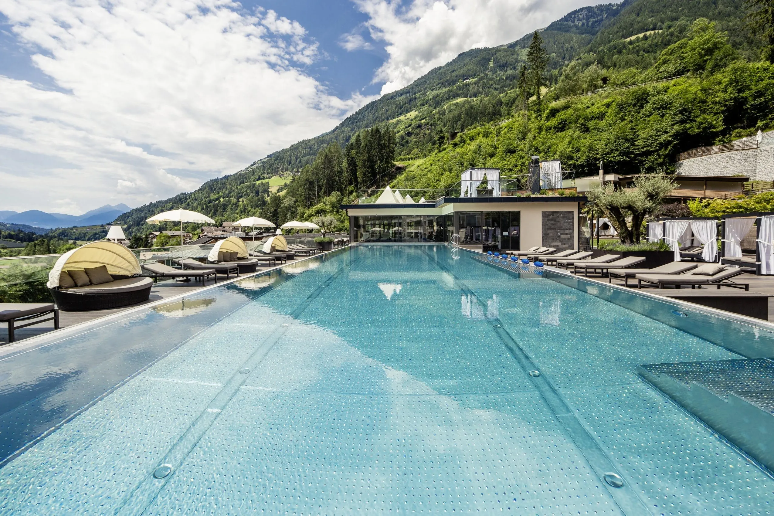 Der Infinitypool mit Daybeds und Blick in die grüne Natur im Quellenhof Luxury Resort Passeier