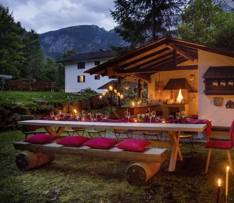 langer rustikal eingedeckter Holztisch vor der urigen Grillhütte im Bayern Resort