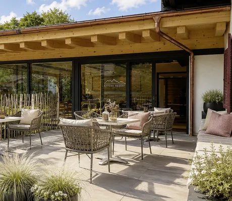 Terrasse des Bayern Resort mit Korbstühlen umgeben von urigem Holzzaun
